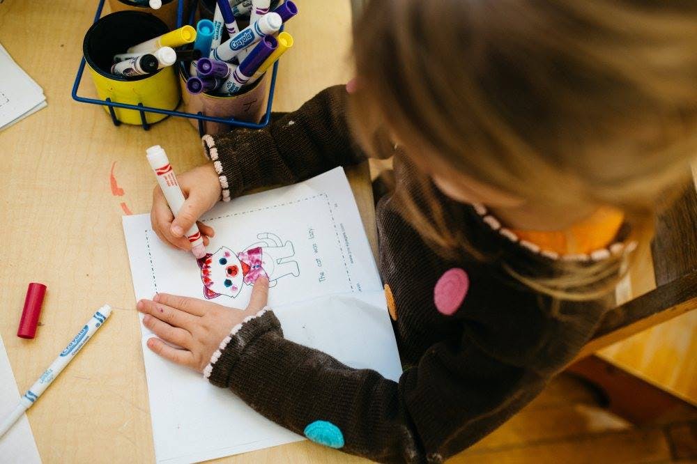 Child coloring a drawing on paper with a marker
