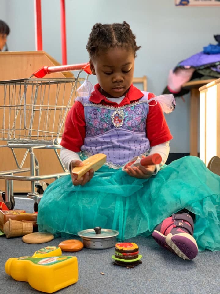 Child playing with toy food on the floor