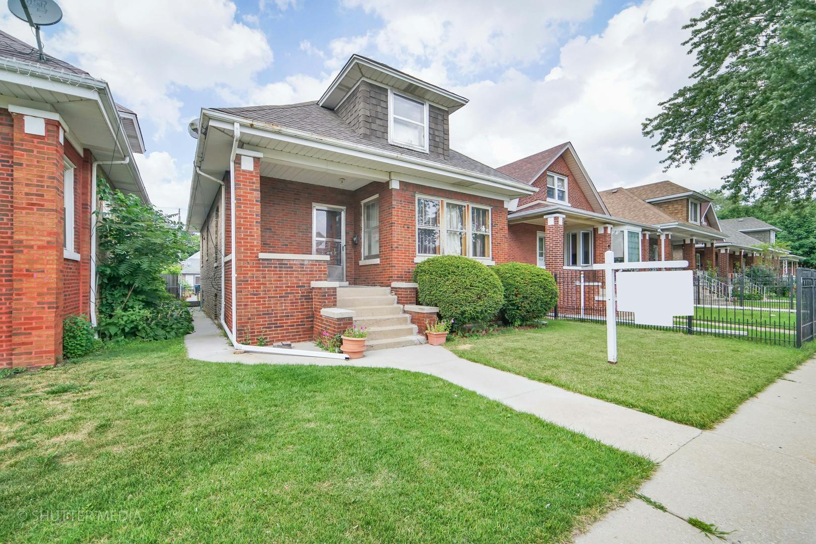 Brick house with a front porch and sidewalk leading to the street