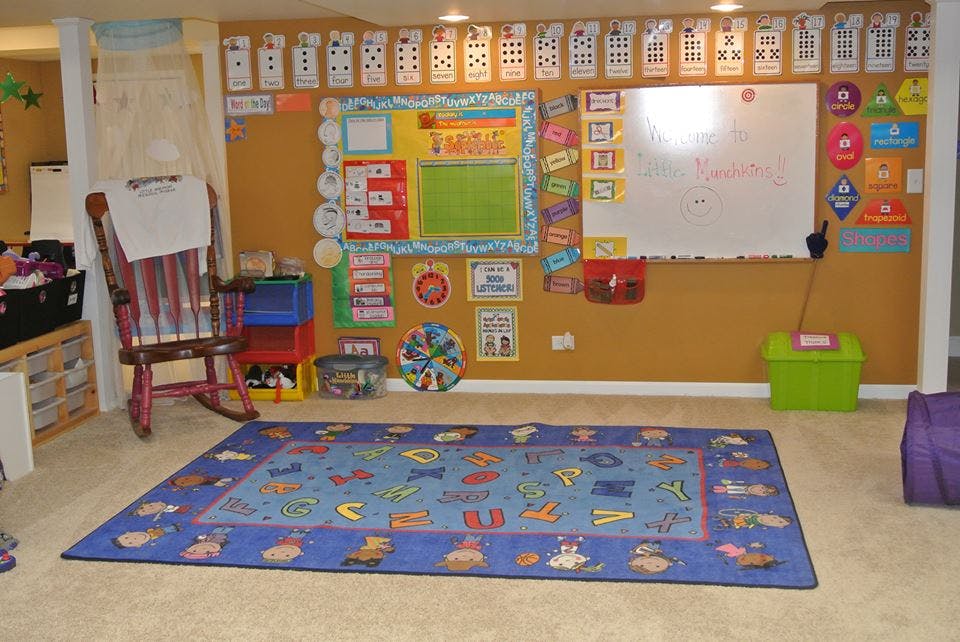 Classroom with a blue alphabet rug, whiteboard, and bulletin board