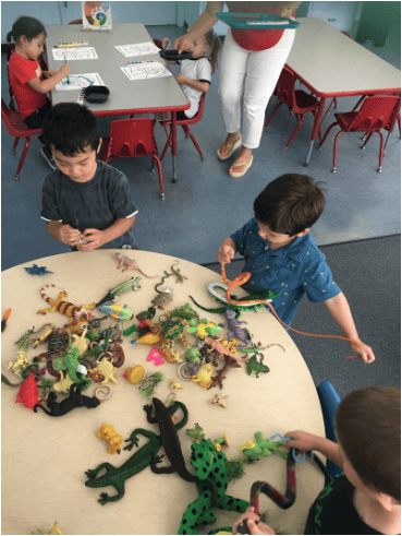 Children playing with toy animals on a table