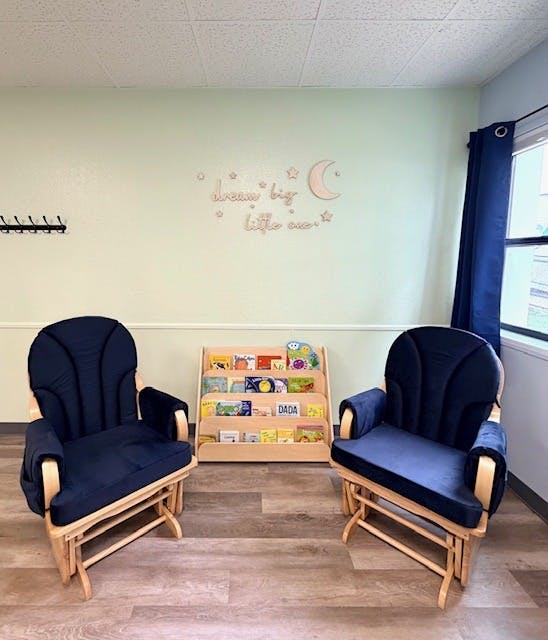 Two rocking chairs facing a small bookshelf filled with children's books