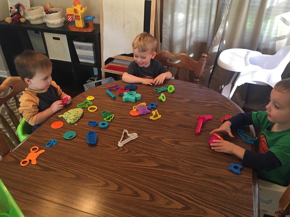 Three children playing with colorful toys at a table