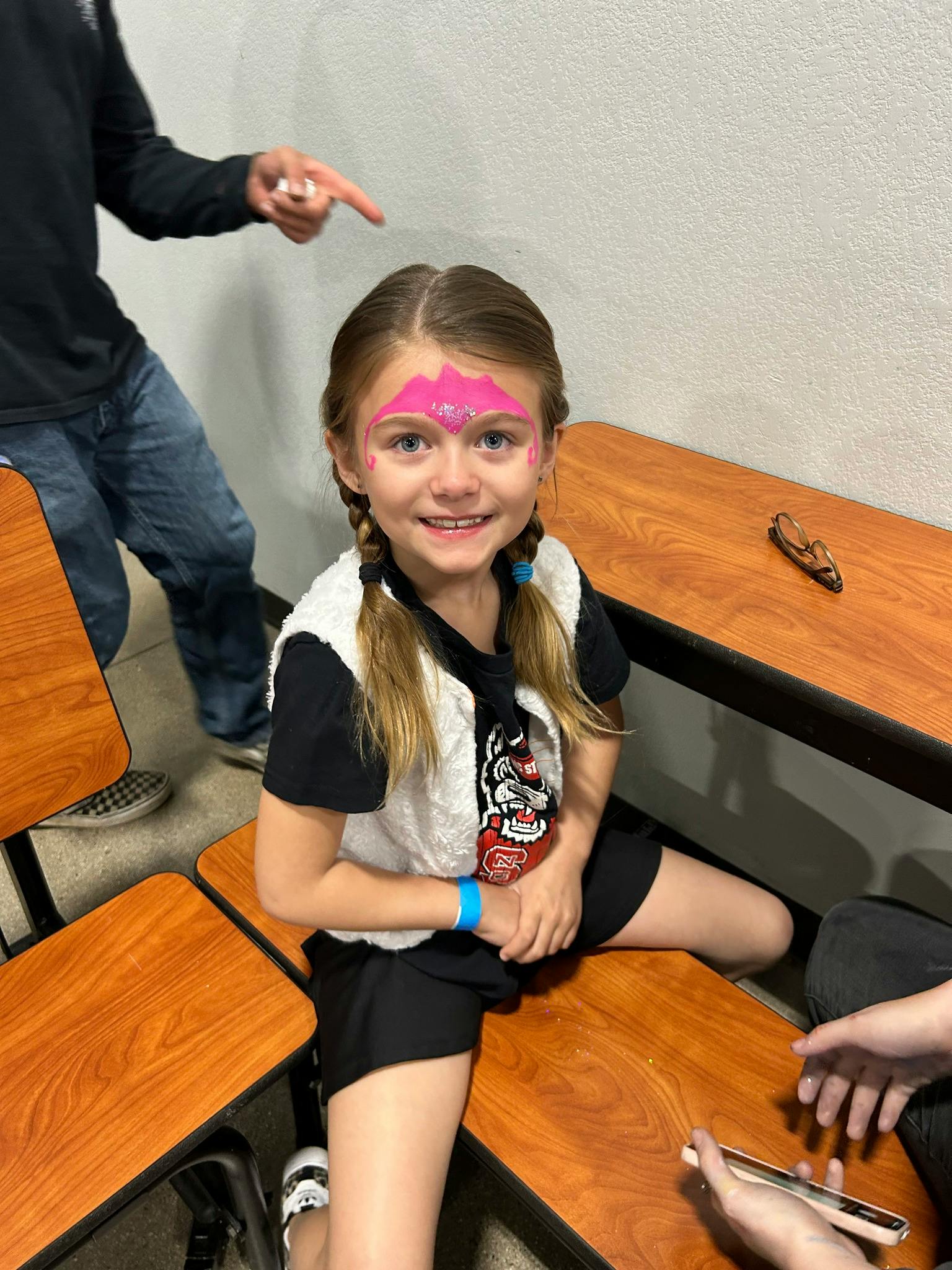 Child with face paint sitting on a bench