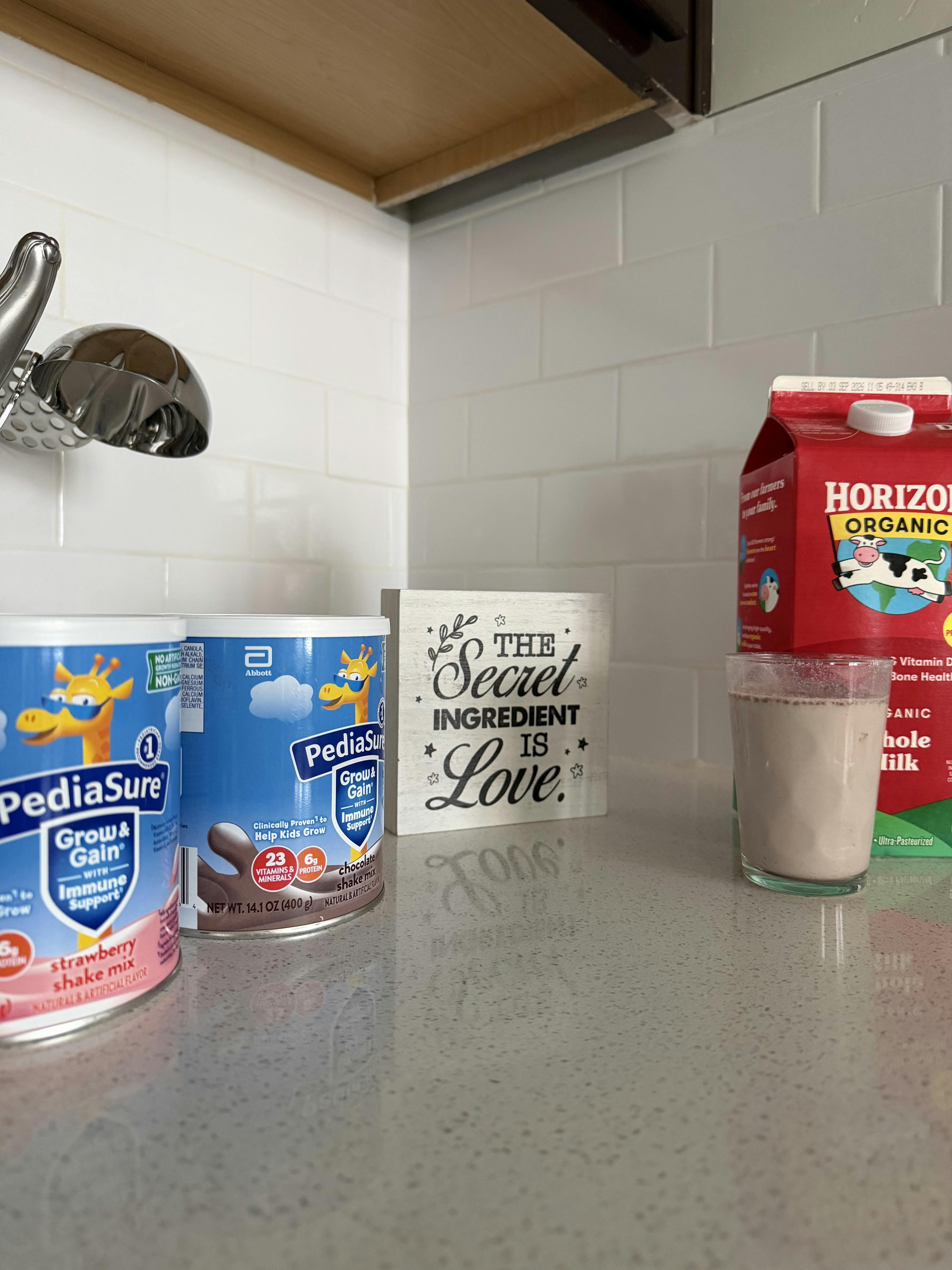 PediaSure shake mix containers and milk on a kitchen counter