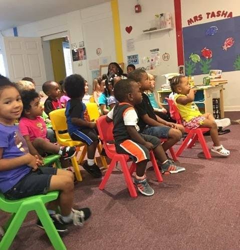 Children sitting on small chairs in a classroom