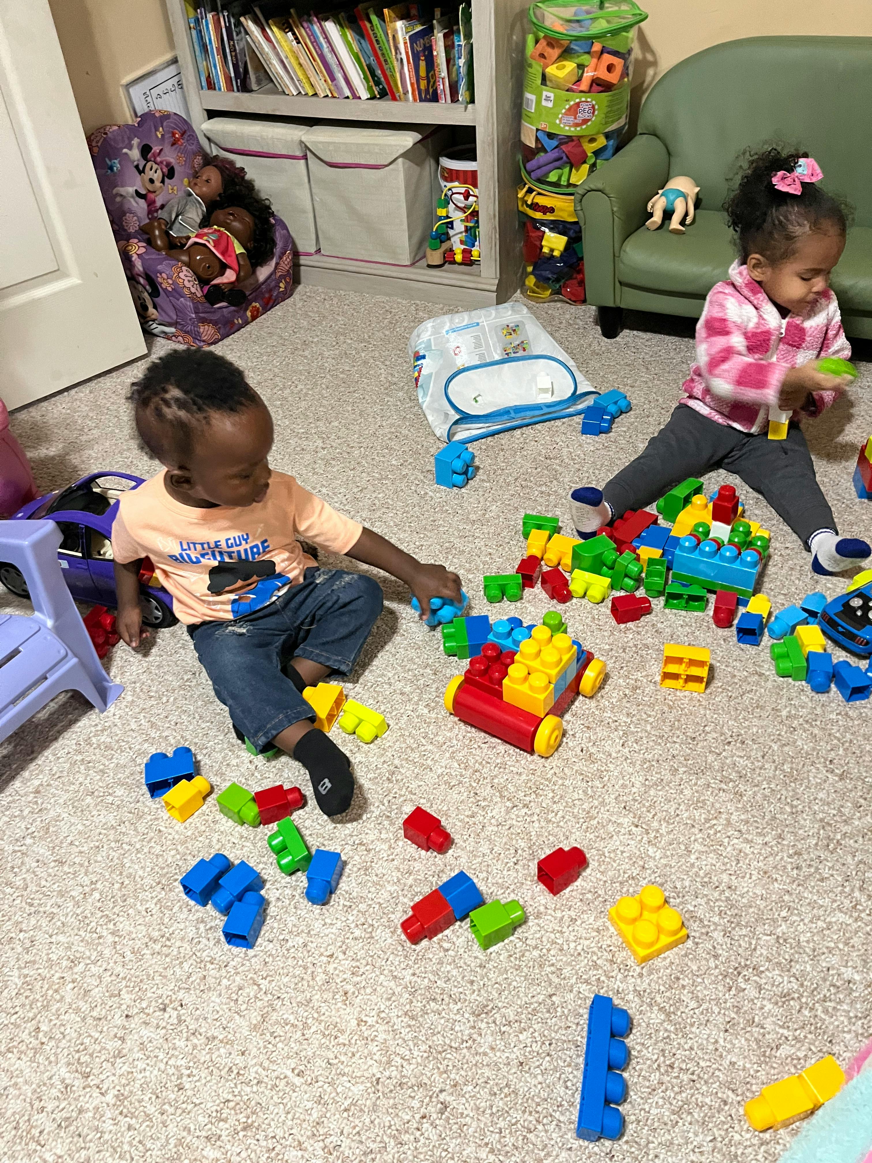 Two children playing with building blocks on a carpeted floor