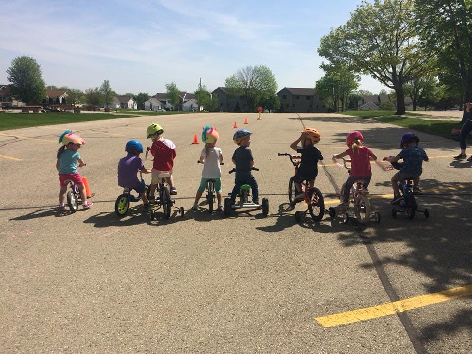 Children on tricycles and bicycles in a paved area