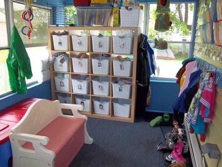 Storage cubbies with white bins in a room with a small bench