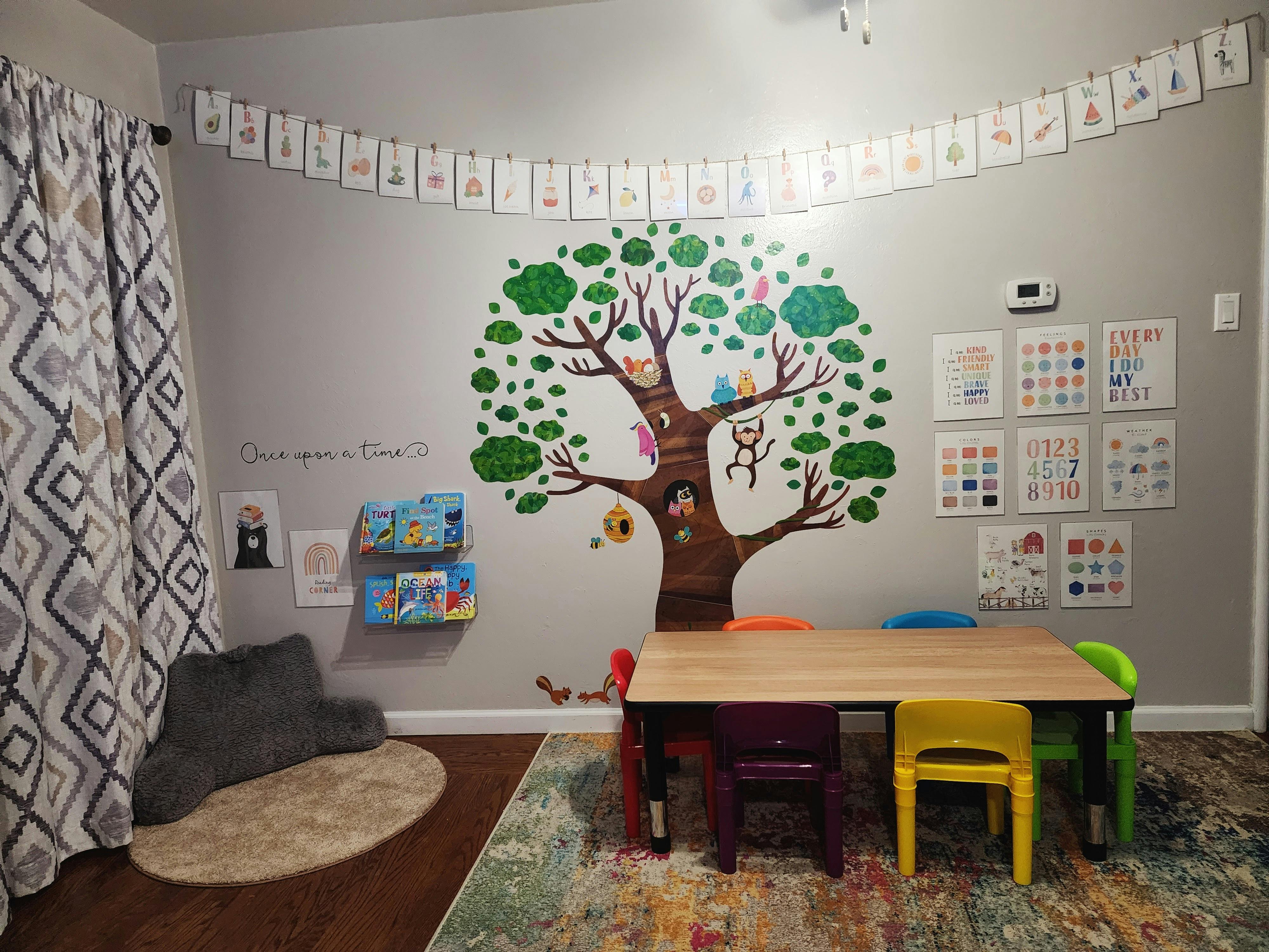 Children's play area with a tree mural, small table, and chairs