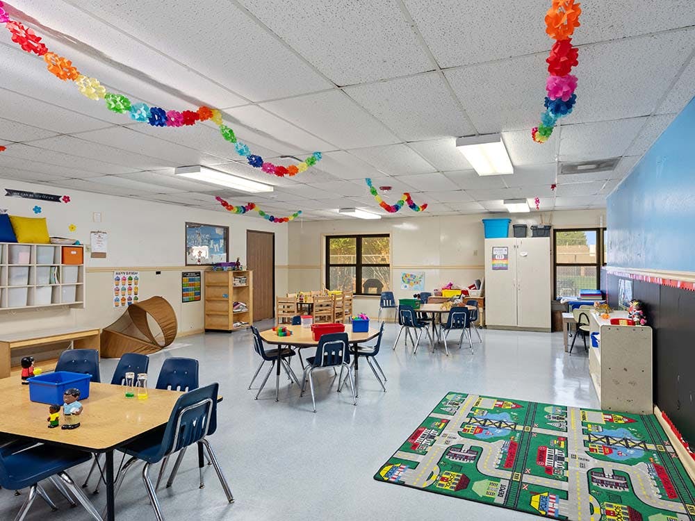 Empty classroom with small tables, chairs, and colorful decorations