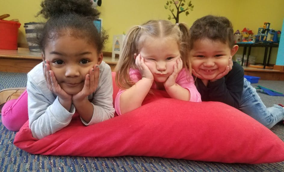 Three children lying on a red pillow