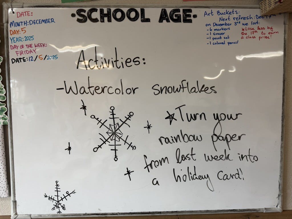 Whiteboard with "School Age Activities" and text about watercolor snowflakes
