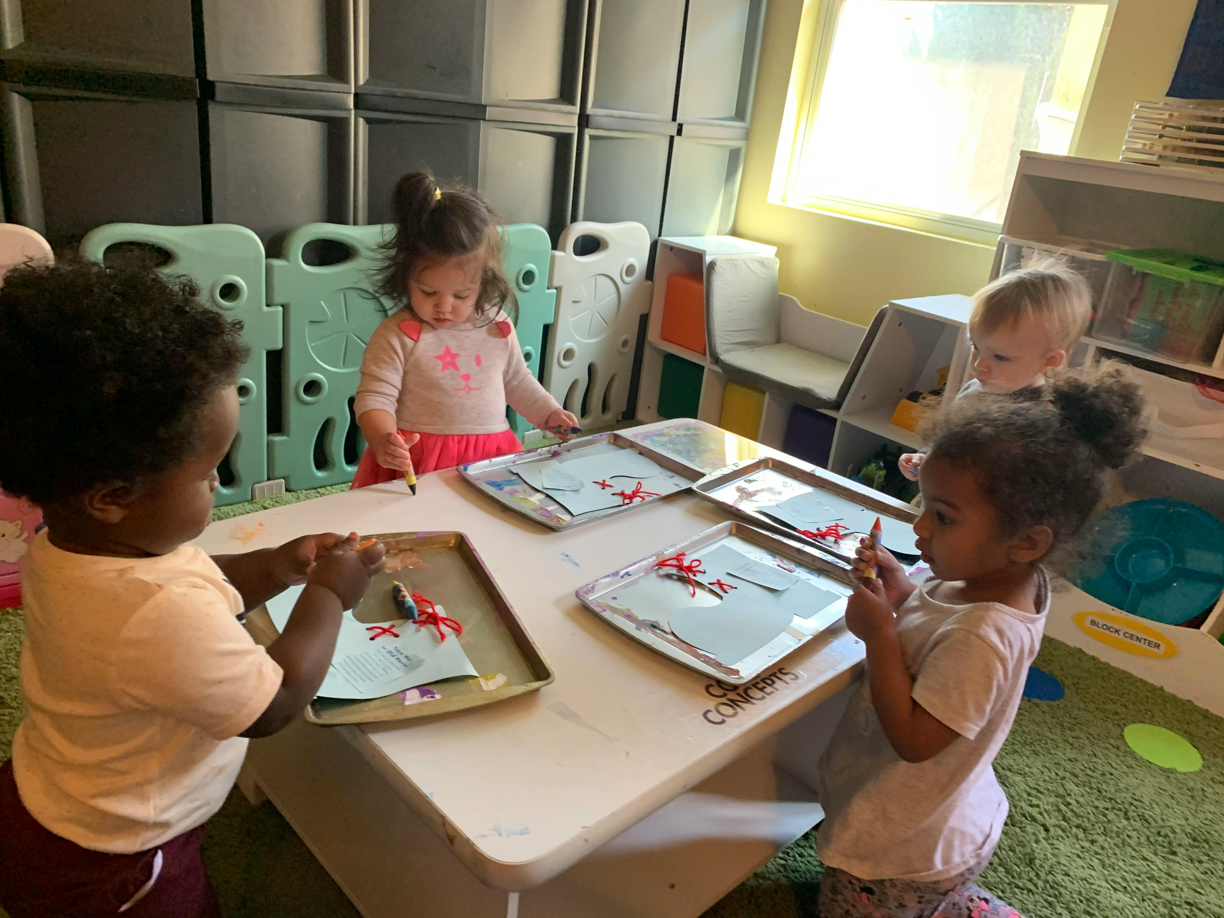 Four children at a table with trays and craft materials