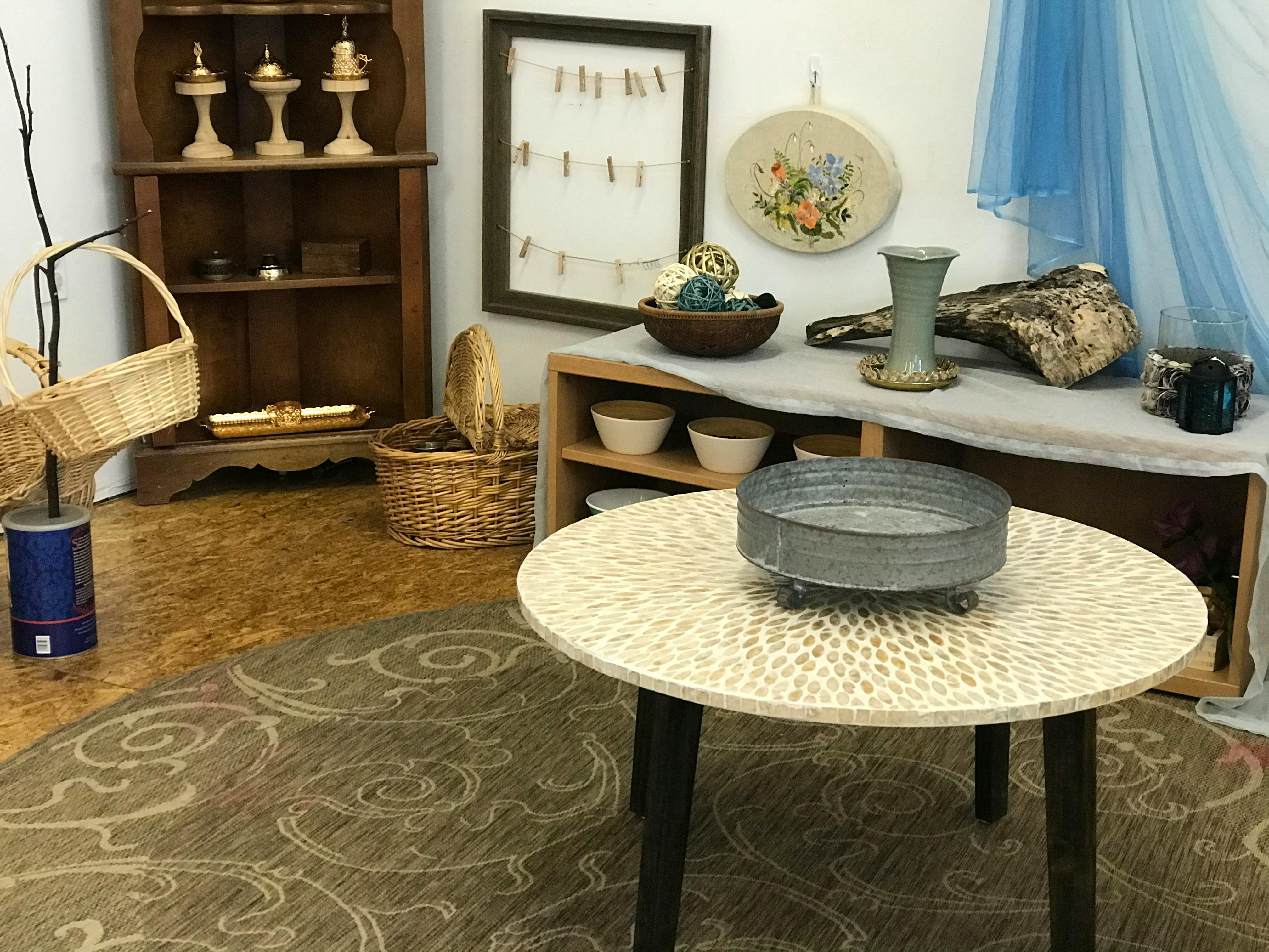Room with a round table, corner shelf, and various decorative objects