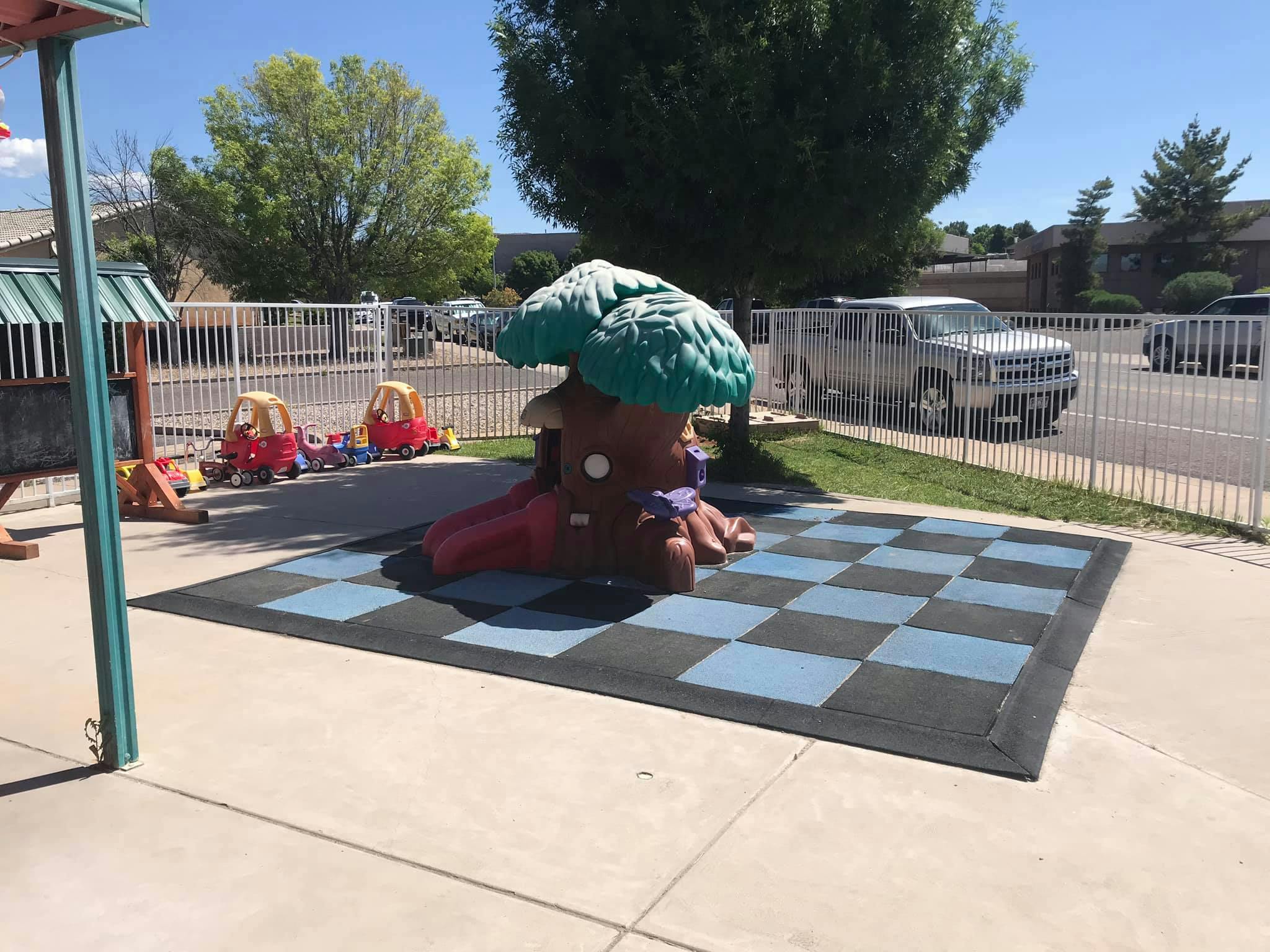 Playground with a tree-shaped slide and a checkerboard mat