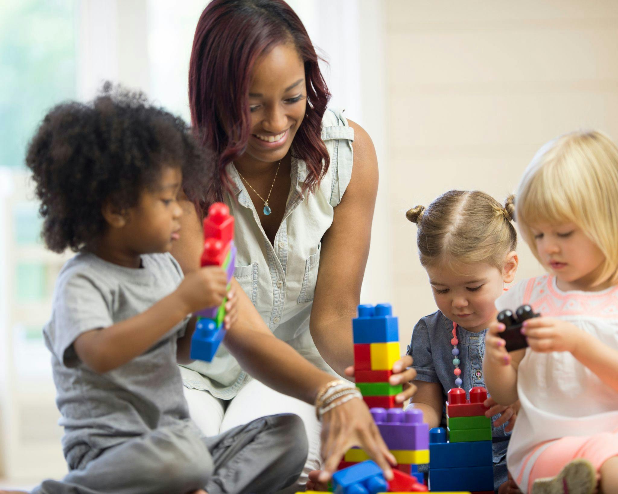 Adult and three children playing with colorful building blocks