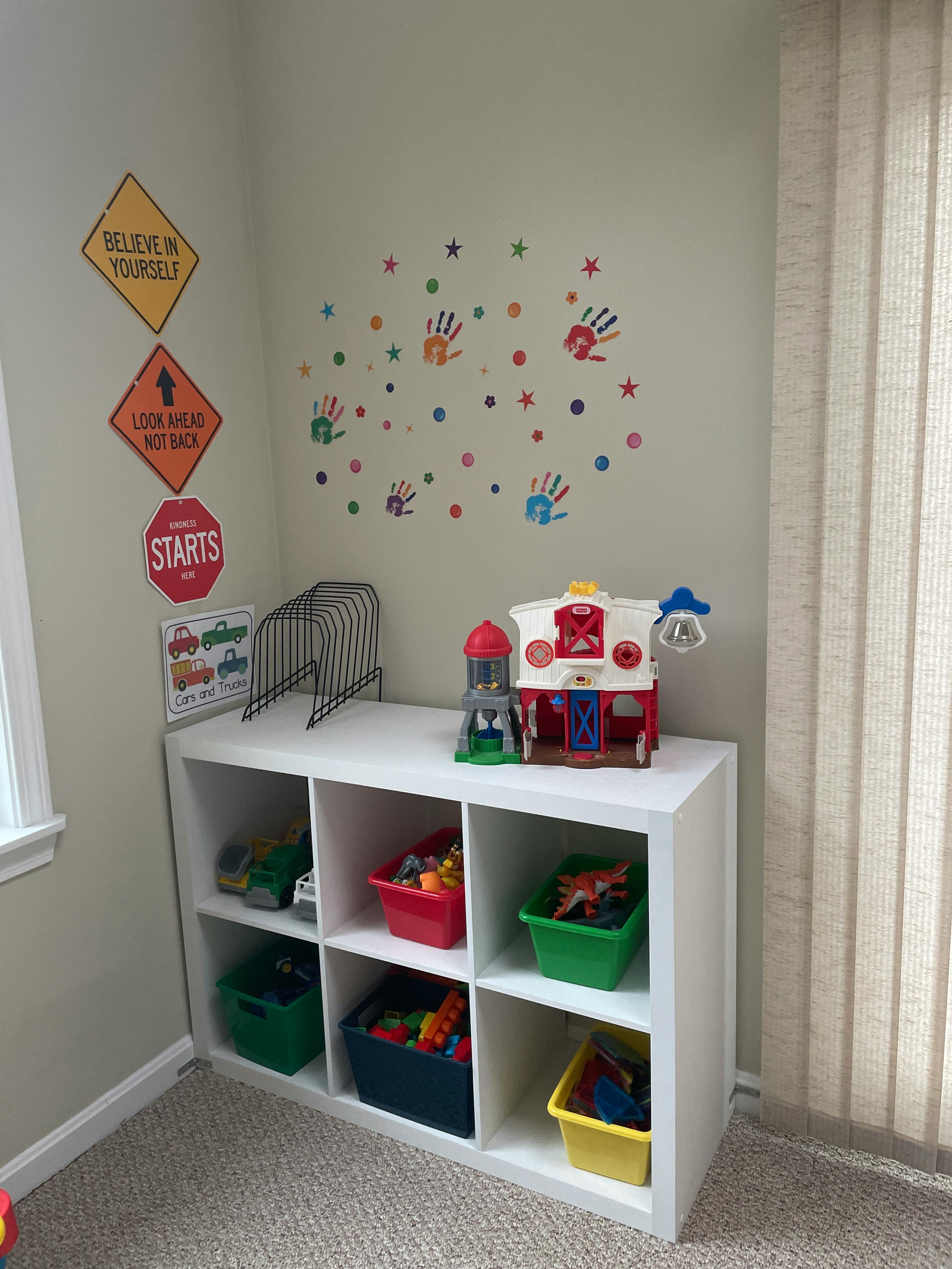 White storage cubby with colorful bins of toys and wall decals