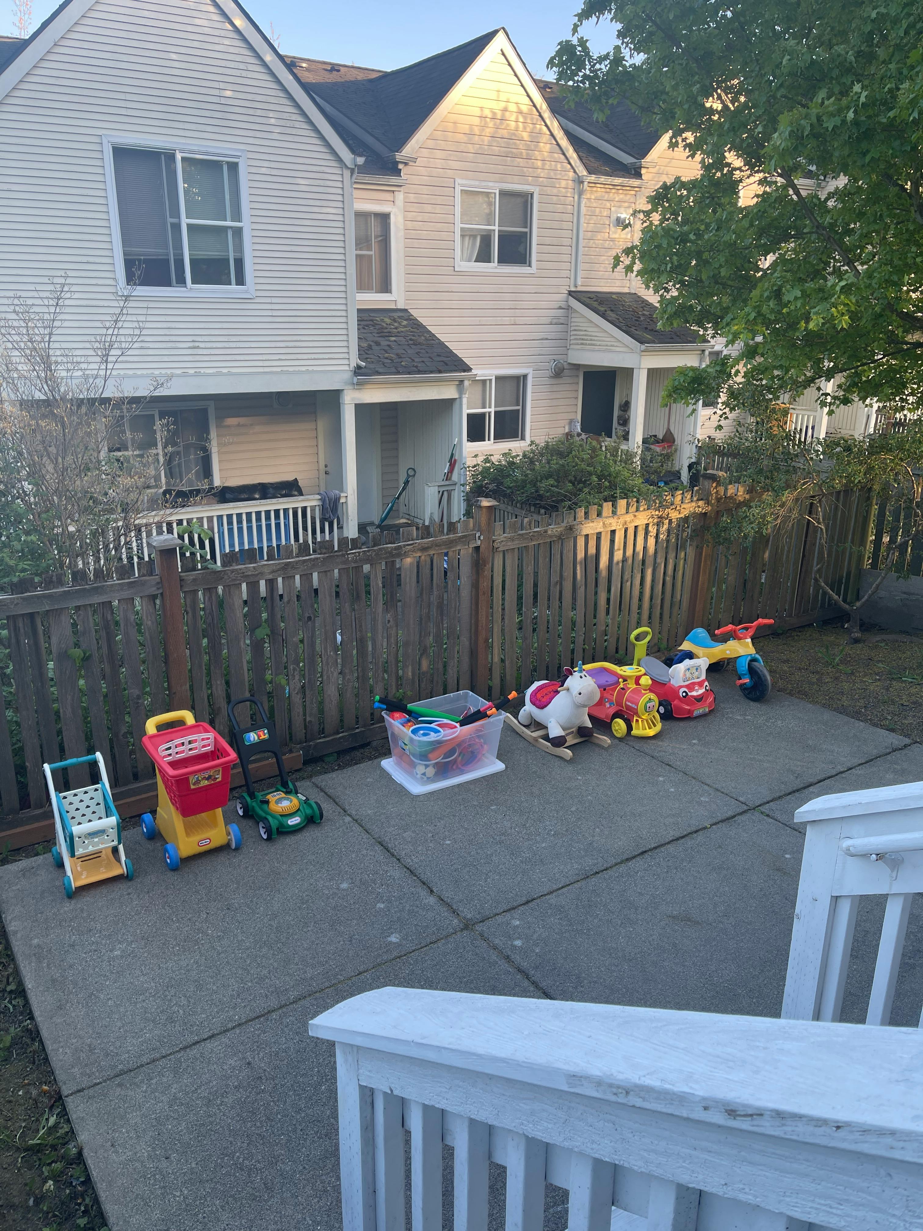 Children's toys on a patio in front of a fence and townhouses