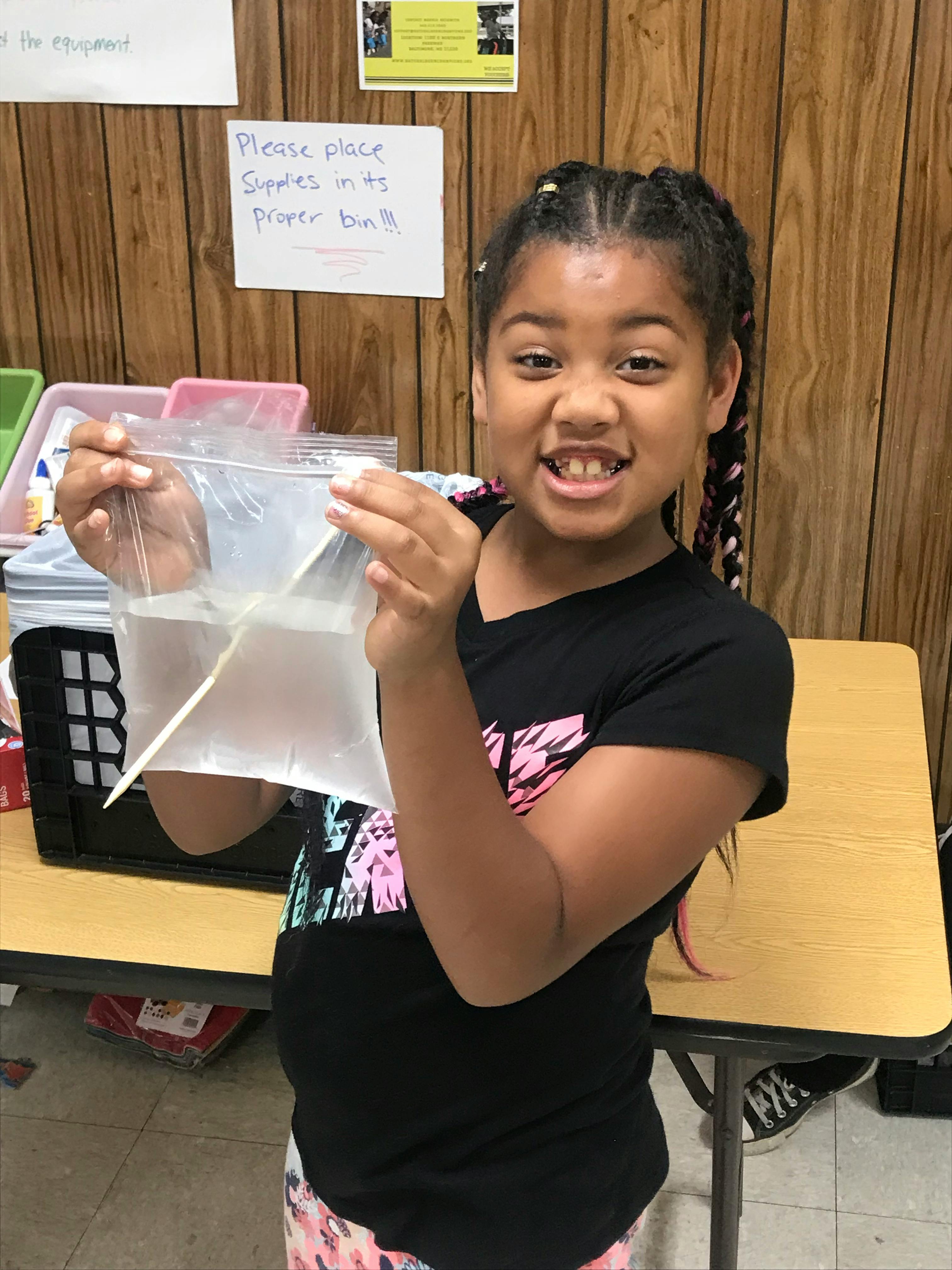 Child holding a plastic bag with water and a stick