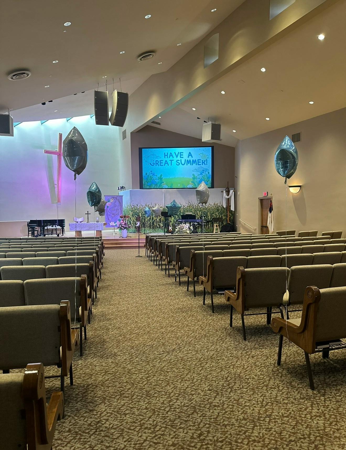 Empty church sanctuary with rows of pews facing a stage with a screen displaying text
