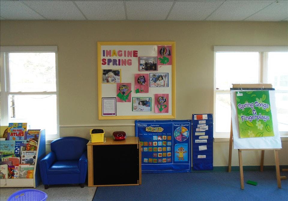 Classroom wall with a bulletin board, chair, bookcase, and calendar