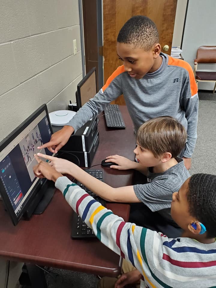 Three children pointing at a computer screen