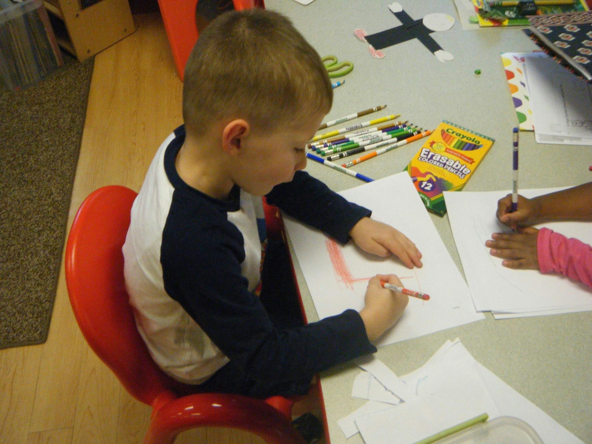 Child drawing on paper at a table