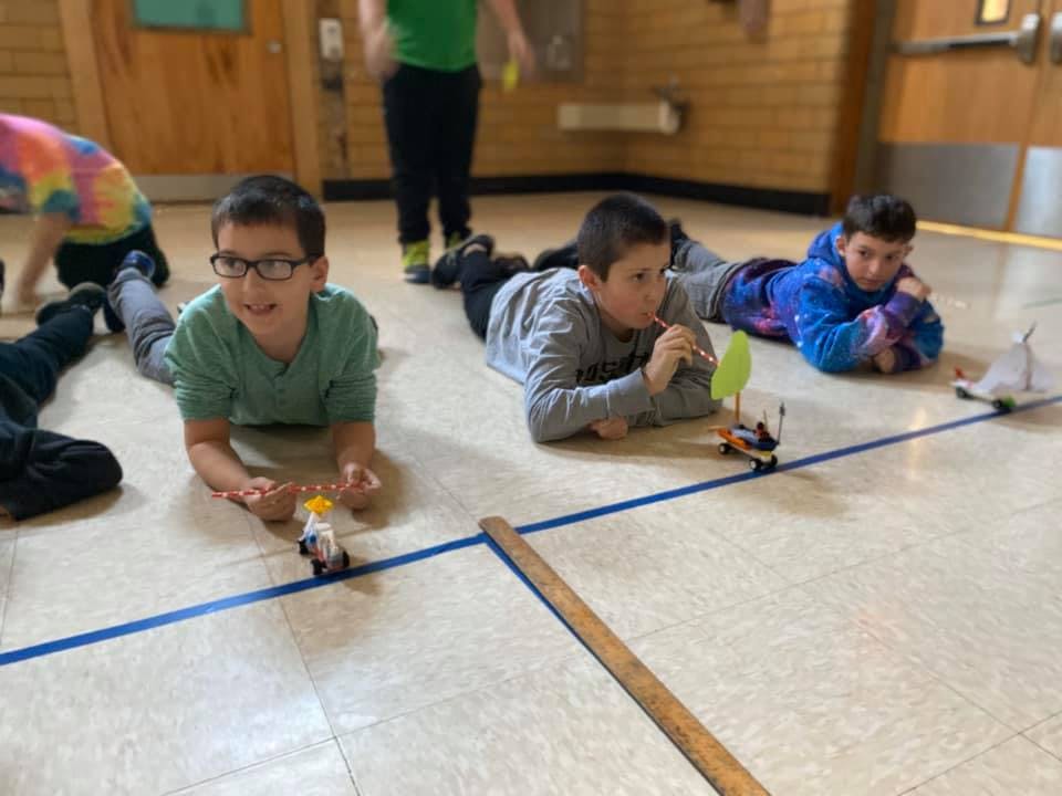 Children lying on floor playing with small toy cars