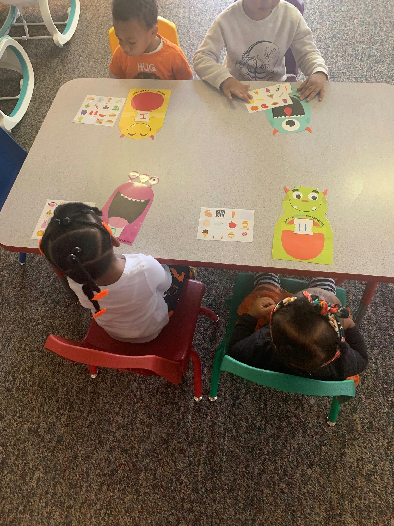 Children sitting at a table with colorful monster cutouts