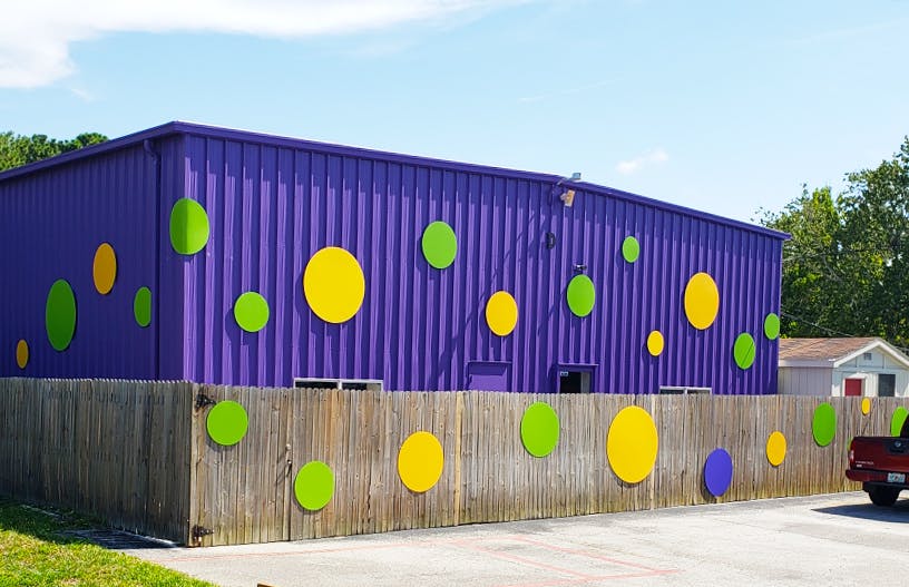 Purple building with green and yellow circles behind a wooden fence