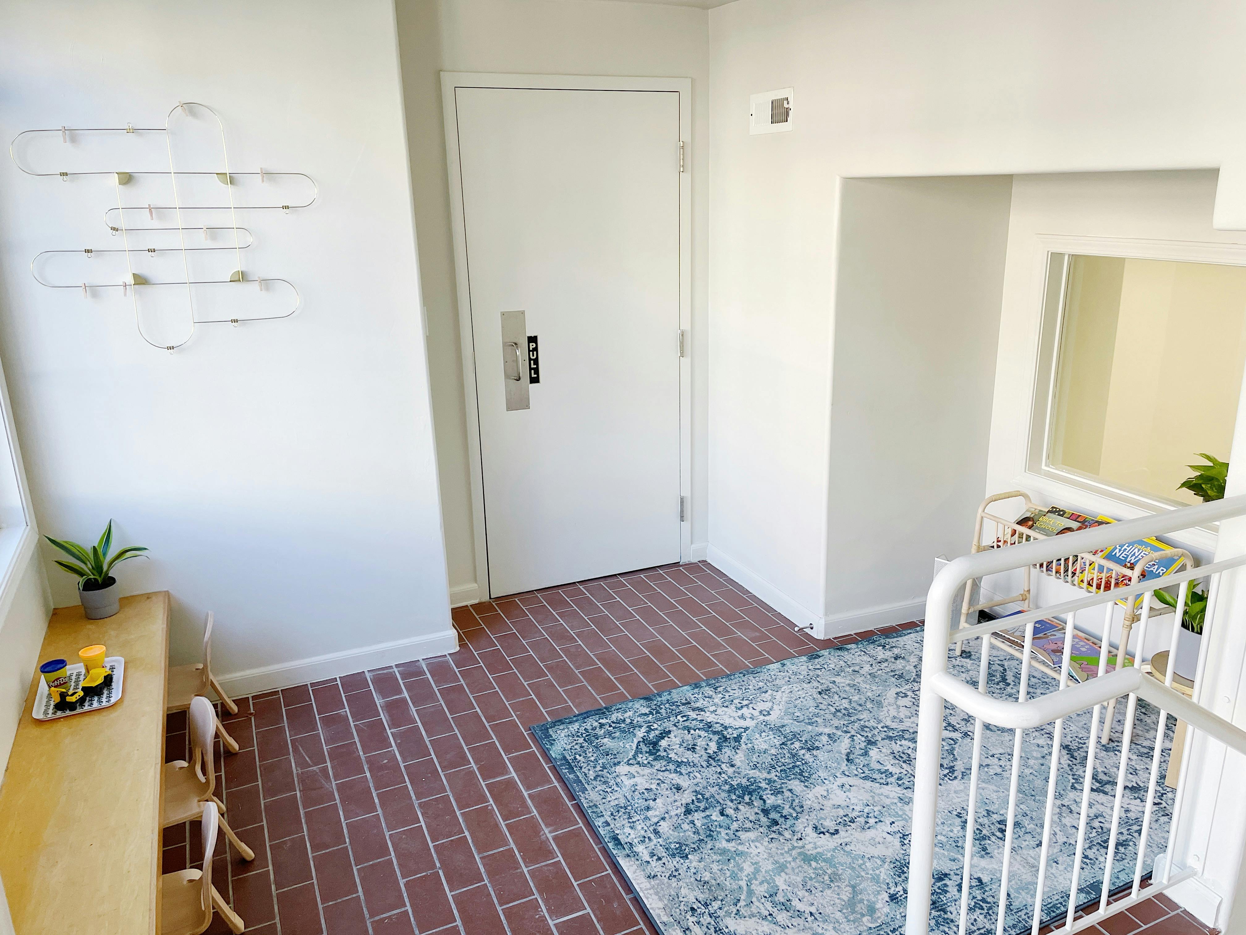 Entryway with brick floor, white door, and blue patterned rug