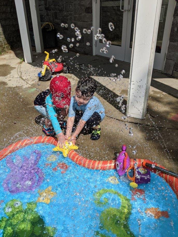 Two children playing with a water sprinkler toy