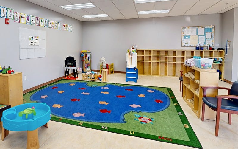 Classroom with a fish-themed rug on the floor, shelves, and educational displays