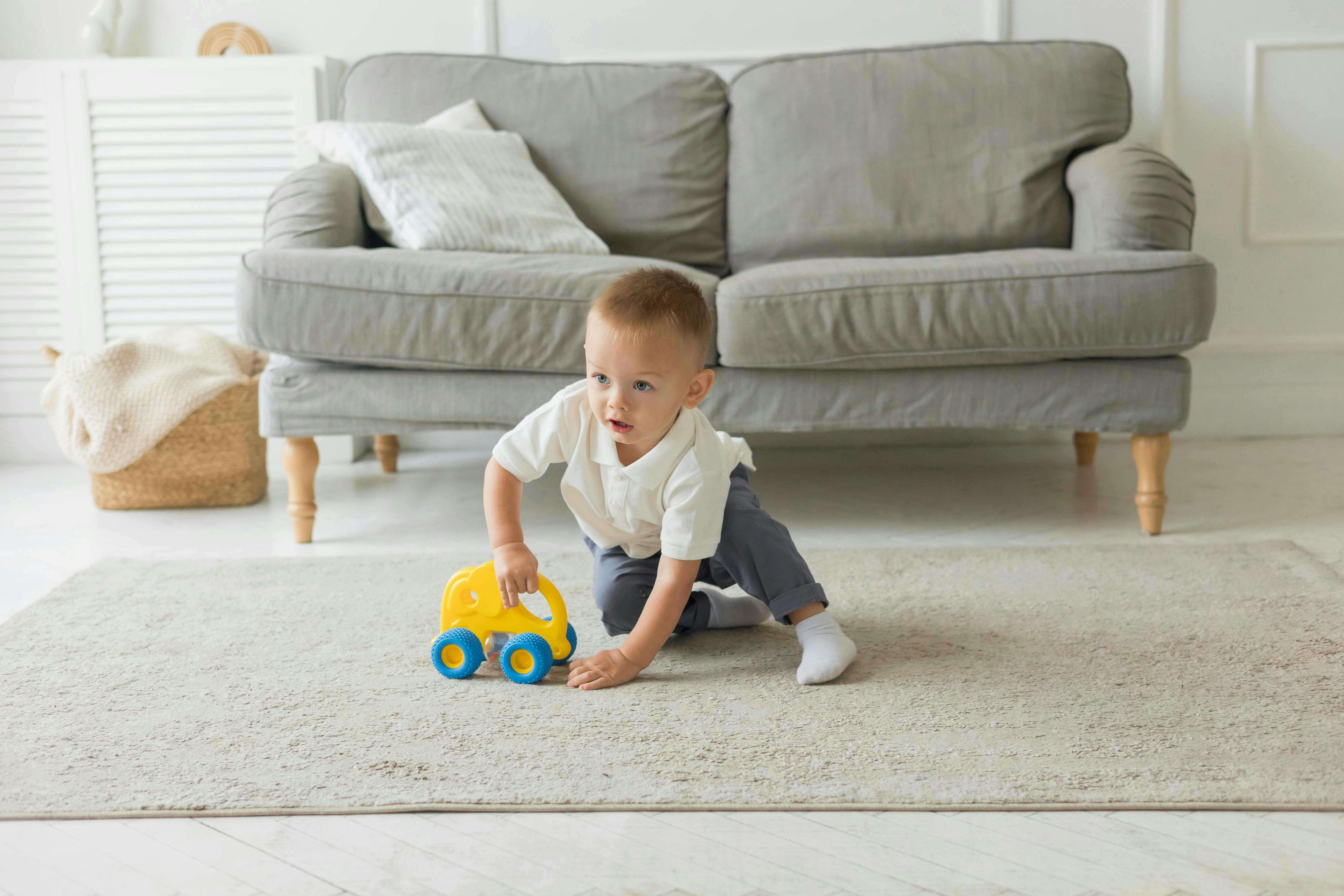 Child playing with a toy car on a rug