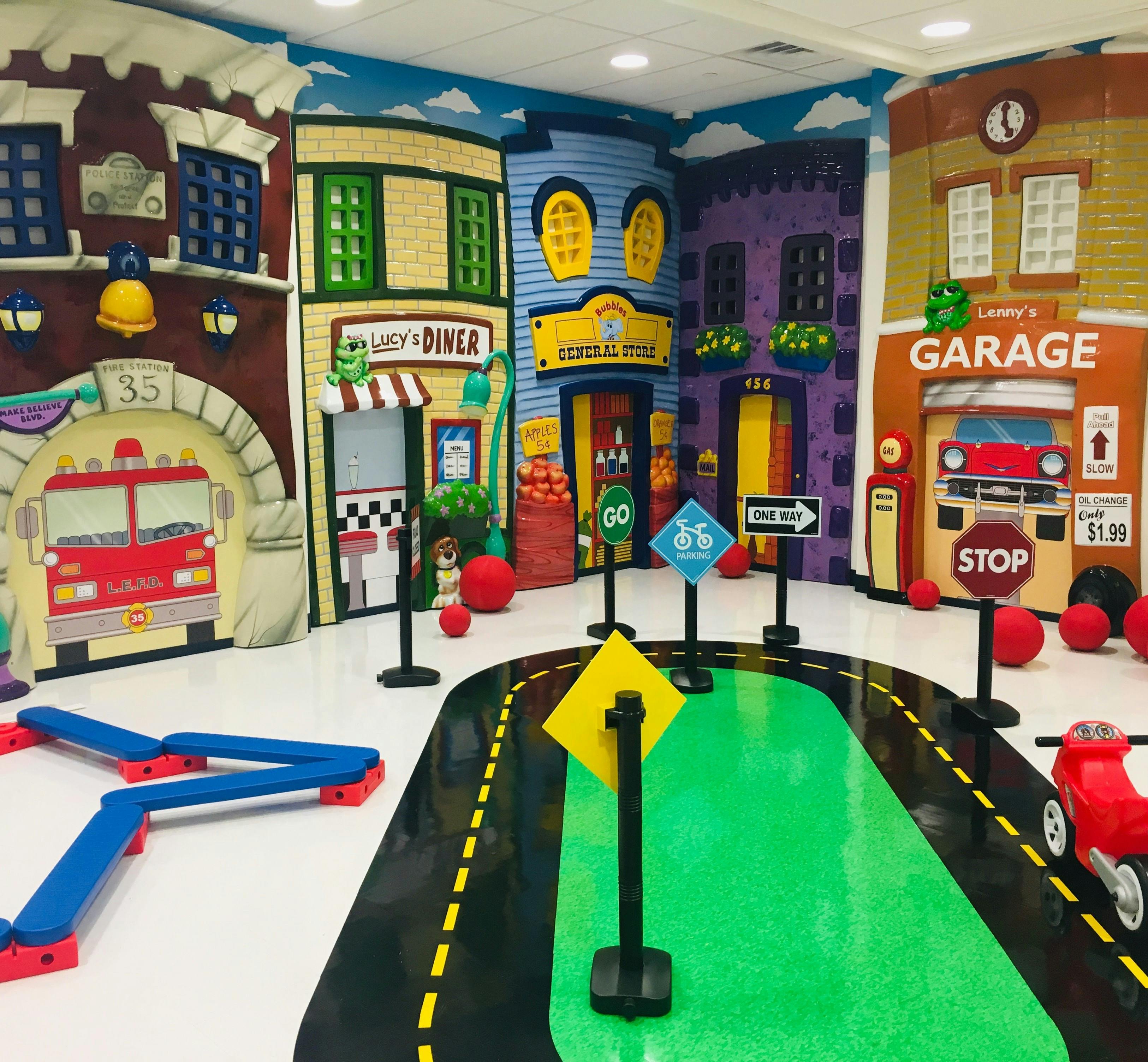 Indoor play area with building facades and a road mat