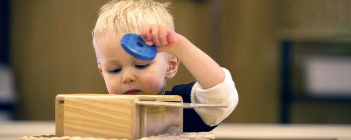Child playing with a wooden toy and a blue disc