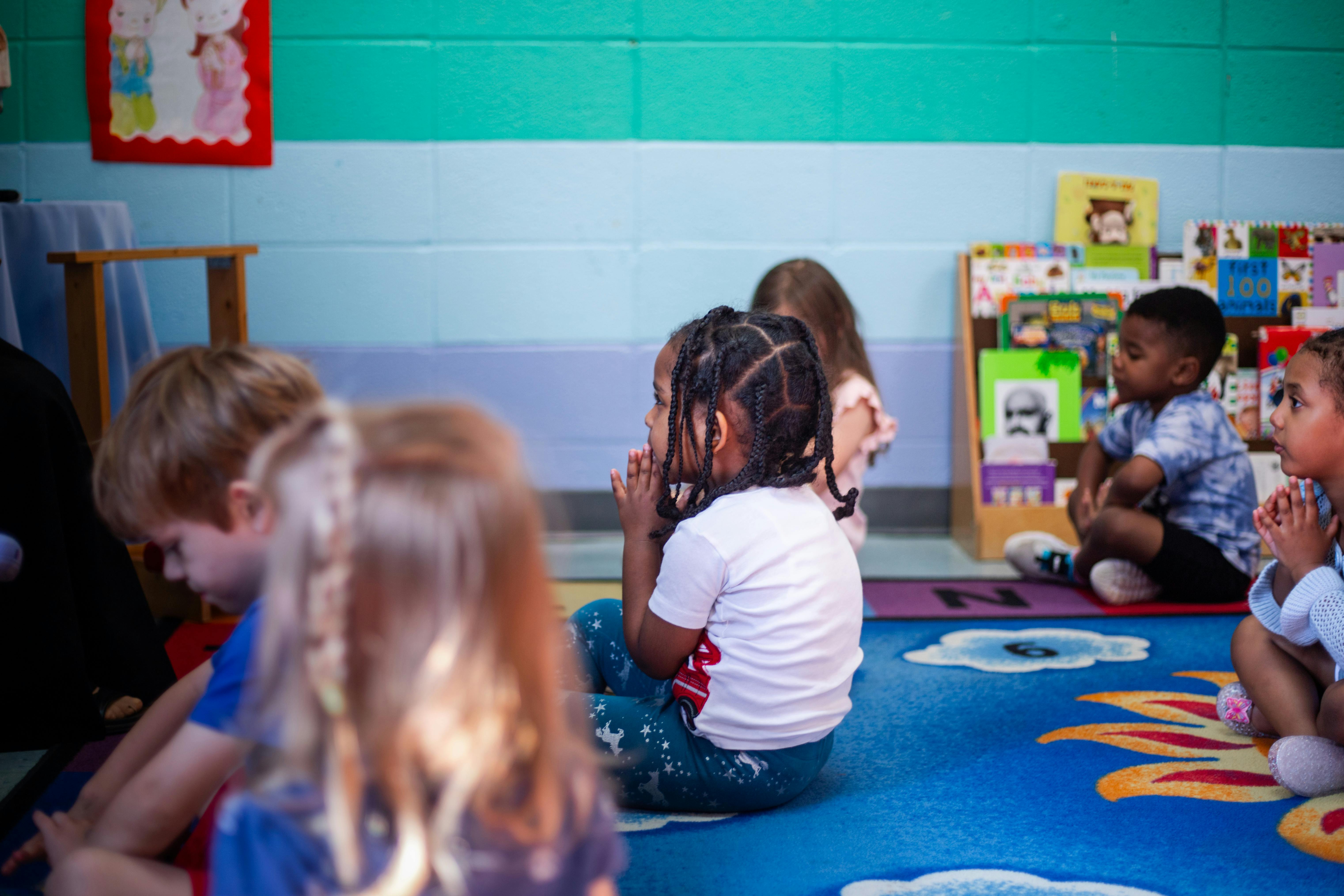 Children sitting on a rug in a classroom