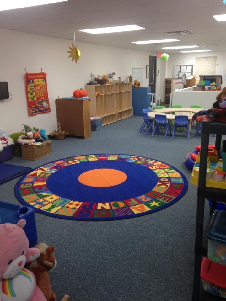 Classroom with a colorful alphabet rug, tables, and shelves