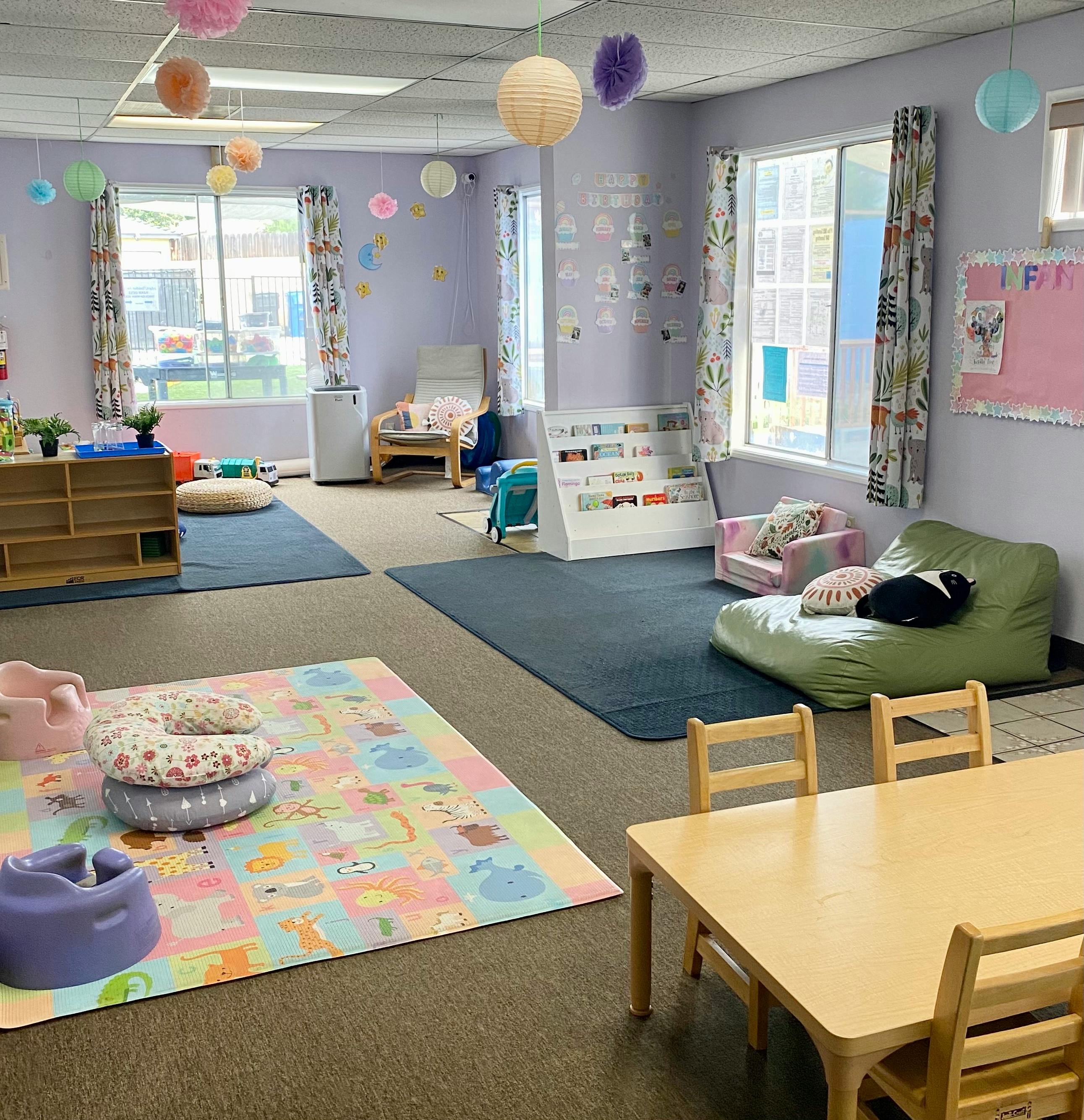 Childcare room with play mats, small tables, and seating areas