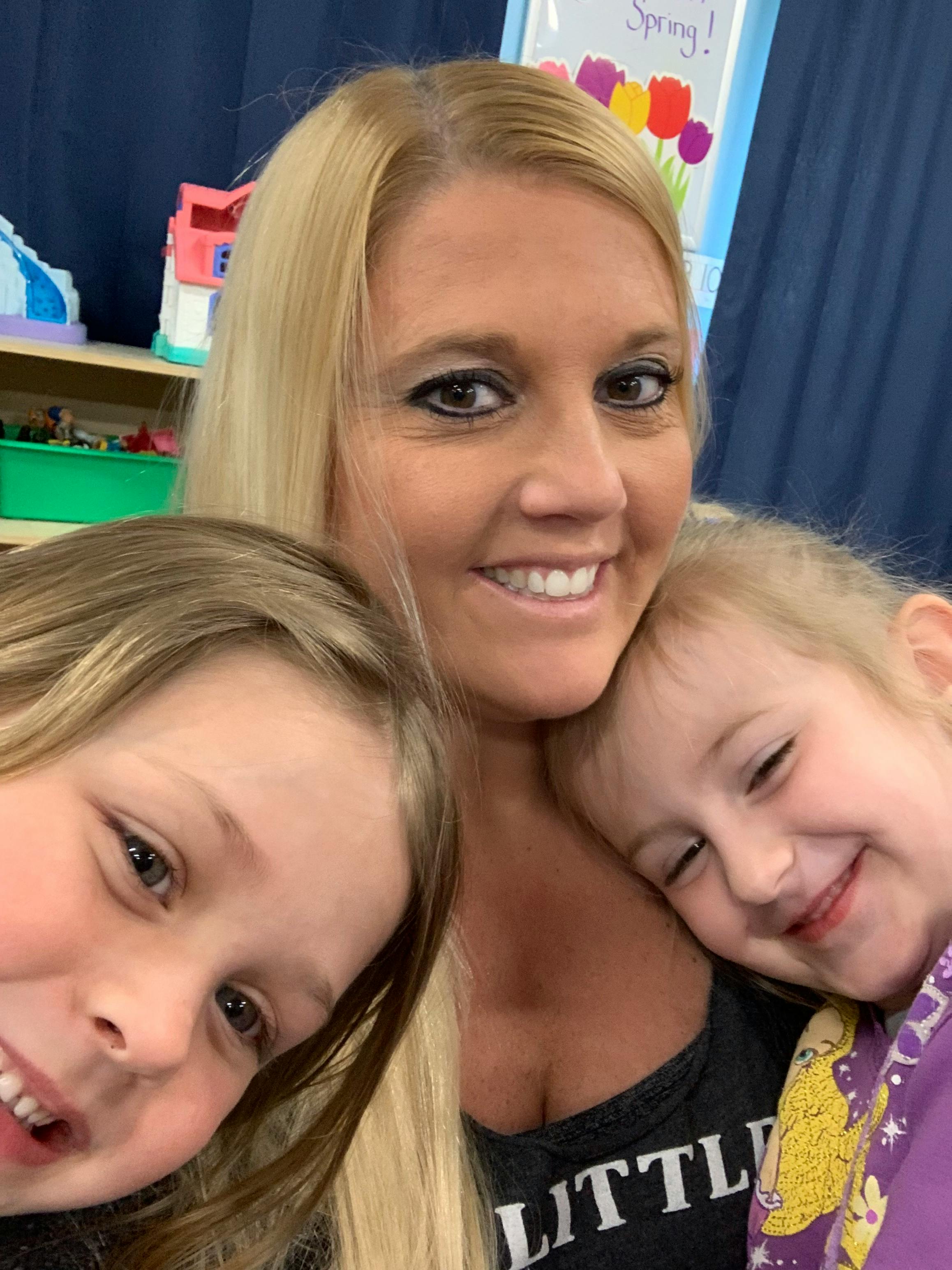 Smiling person with two children in a classroom