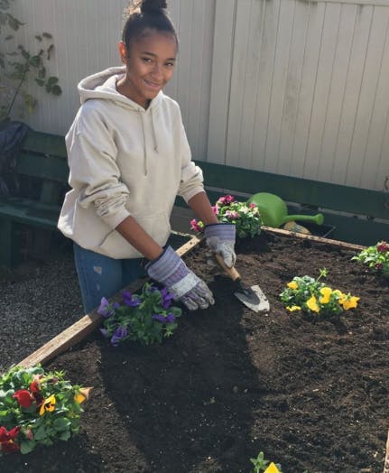 Teen planting flowers in a garden bed