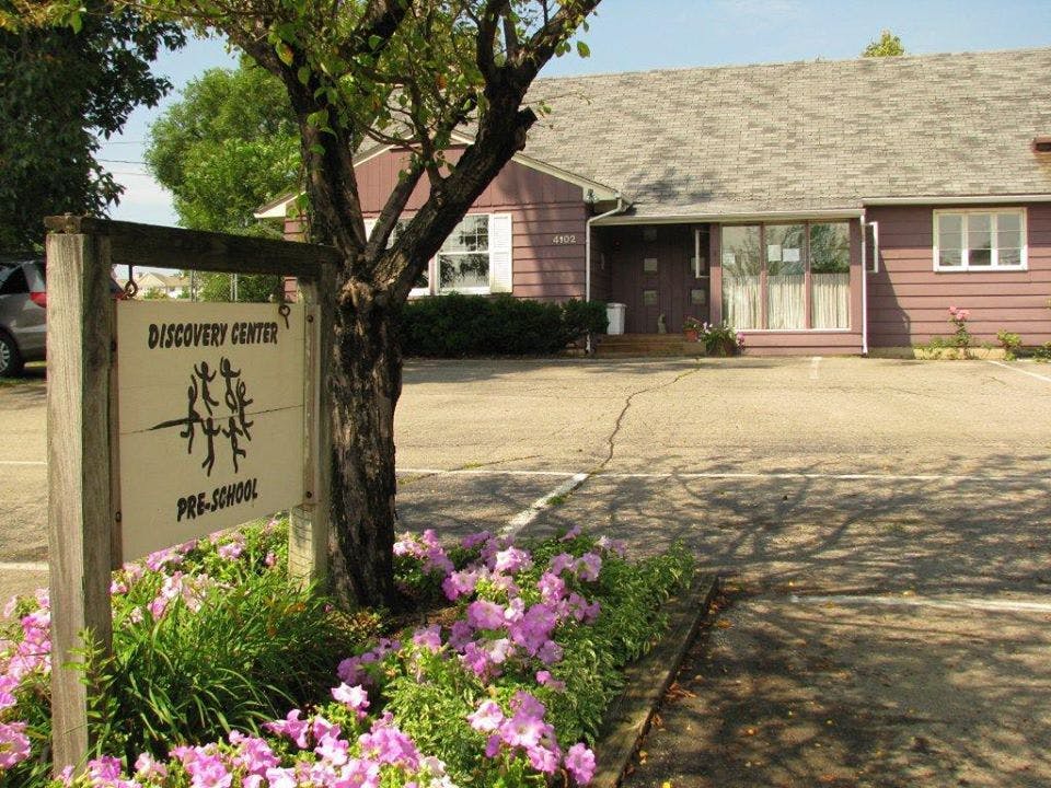 Discovery Center Pre-School sign with a building in the background