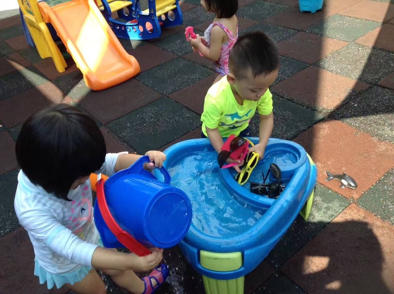 Two children playing with water table and toys