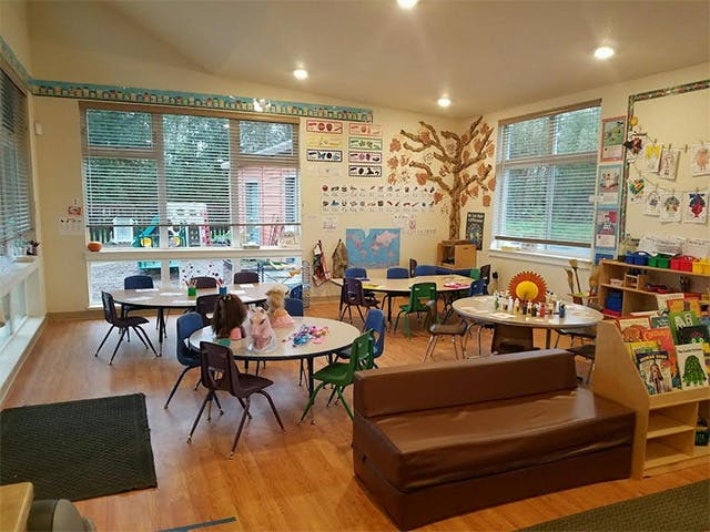 Classroom with small tables and chairs, a brown couch, and windows