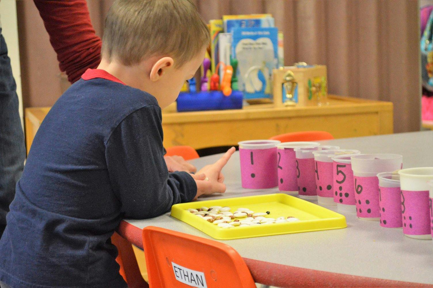 Child at a table with counting cups and small objects