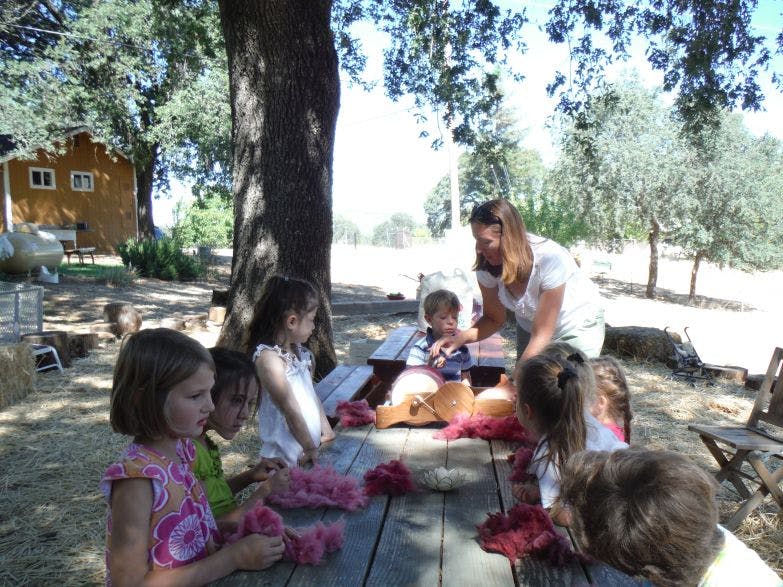 Adult and children at a picnic table with craft materials