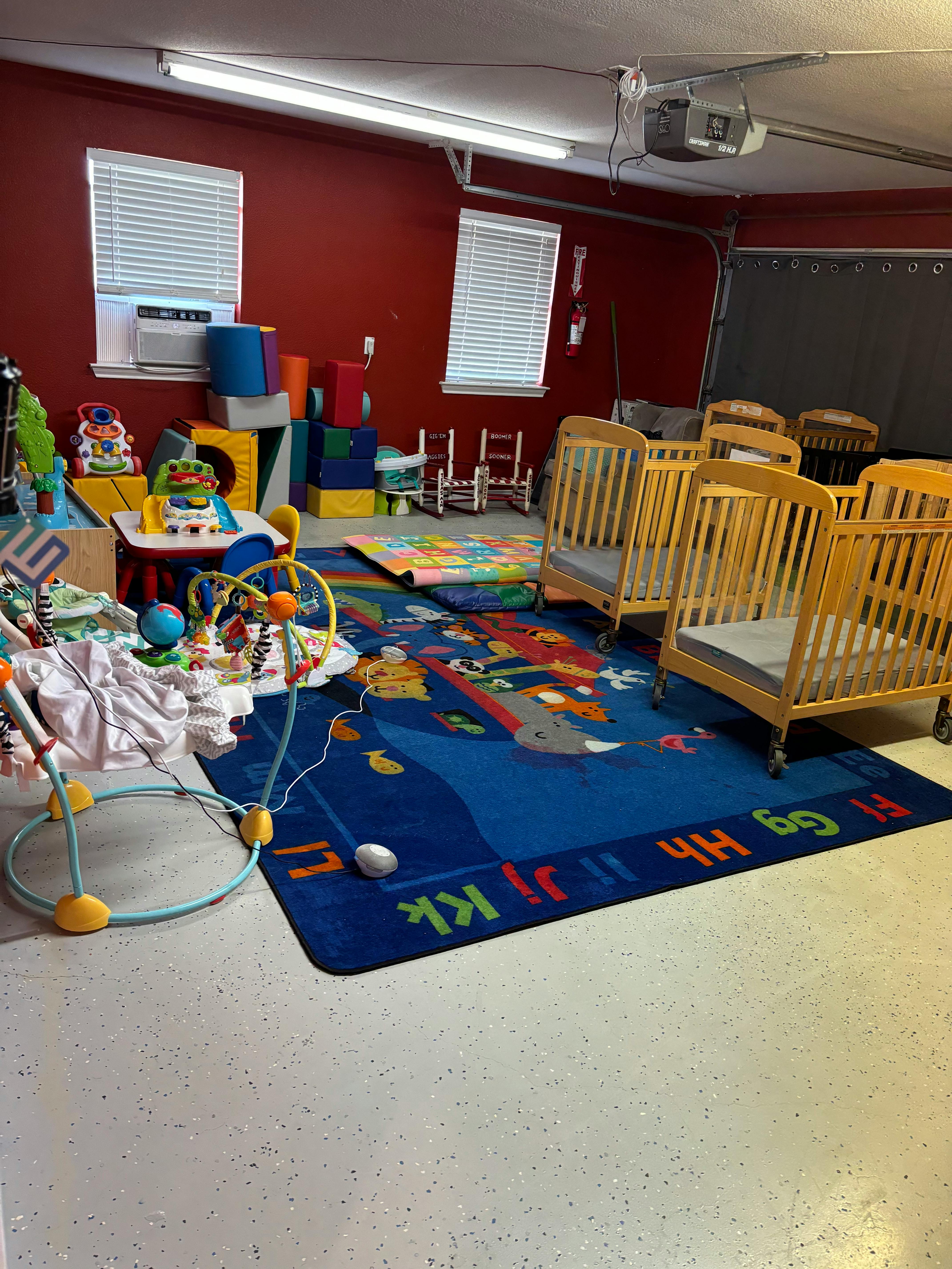 Room with multiple cribs, play mats, and children's toys