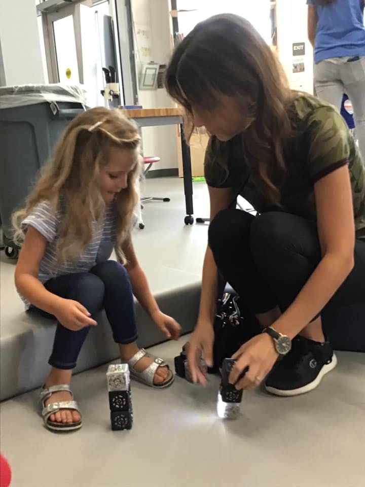 Adult and child looking at small devices on the floor