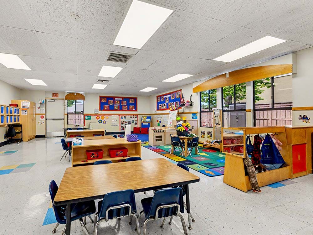 Empty preschool classroom with tables, chairs, and colorful play areas